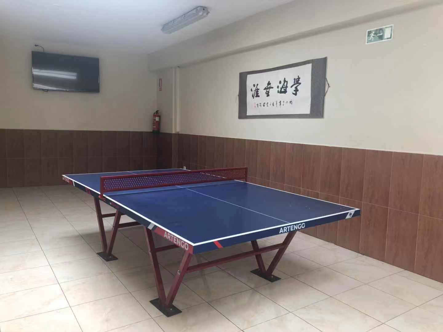学校宽敞的活动大厅，配有乒乓球桌等活动器材